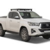 Image montrant le kit de galerie Slimline II conçu pour le Toyota Hilux Revo Extra Cab. Ce kit comprend un plateau Slimline II, des pieds de montage et un déflecteur de vent, offrant une solution de transport robuste et pratique pour augmenter l'espace de stockage sur le toit du véhicule.